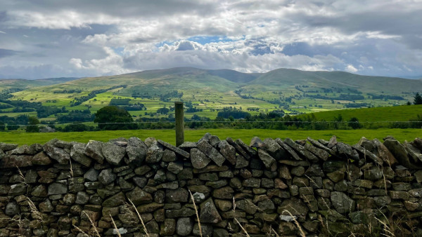 View of a Cumbrian landscape with fells looked at over a dry stone wall.