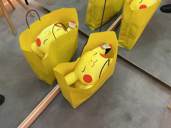 A sleeping Pikachu plush in a yellow shopping bag. He is comfy. 