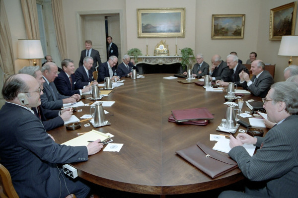 Fifteen white guys sitting around a large oval table, with coffeepots and manila folders.  Reagan and Gorbachev sit on opposite sides, both flanked by advisers, all wearing ties and jackets.