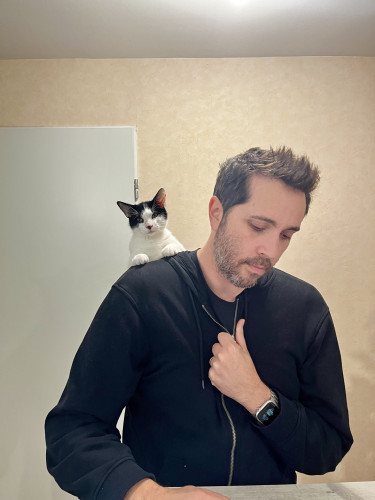 Photo de mon chat Rémy posé sur l’épaule de mon mari. on peut imaginer que ce son derrière est installé dans la capuche.