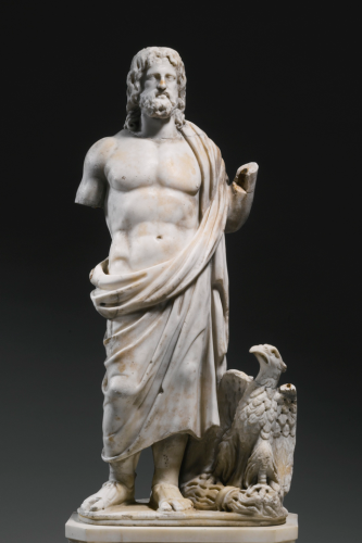 Marble statue of a bearded Zeus dressed in a himation cloak worn over his left shoulder. His arms are missing but he likely originally carried a sceptre. An eagle perches at his feet, its talons on his thunderbolt.