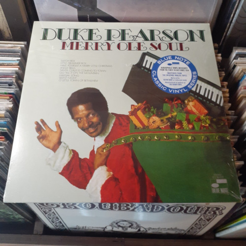Album cover features photograph of DP dressed as Santa Claus and waving. He's carrying a large green sack of presents, including a piano keyboard.