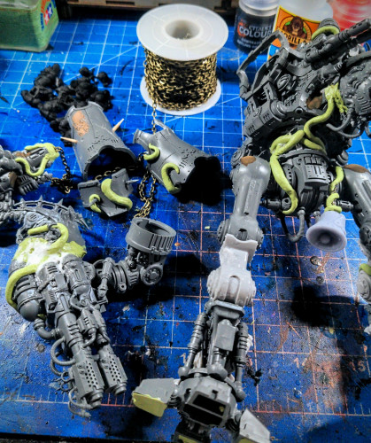 Various pieces of a Nurgle-themed Chaos Knight Tyrant from Games Workshop scattered over a hobby desk.