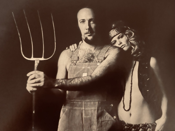 Herbie Mann with a young lady leaning on him, holding a pitchfork reminiscent of the American Gothic painting