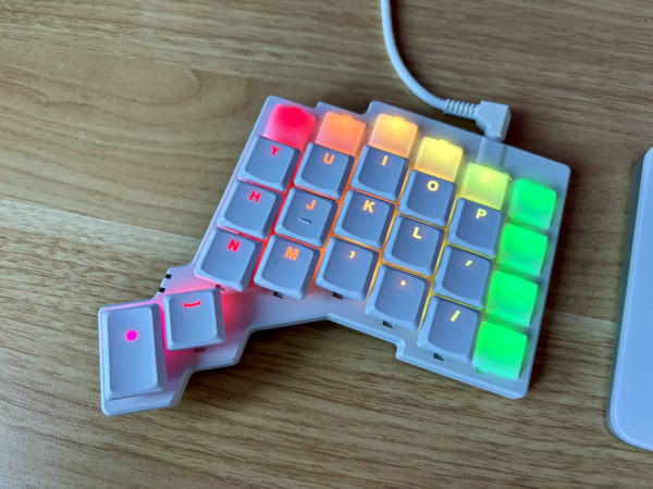 Right half of split mechanical keyboard with LED backlighting illuminated in a rainbow pattern.
