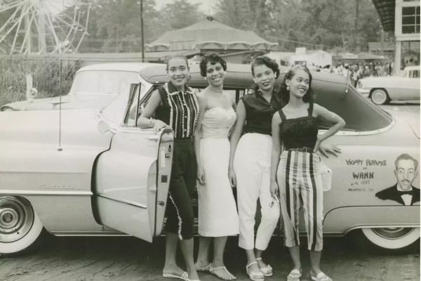 Four young women standing beside a convertible automobile, ca. 1958.

