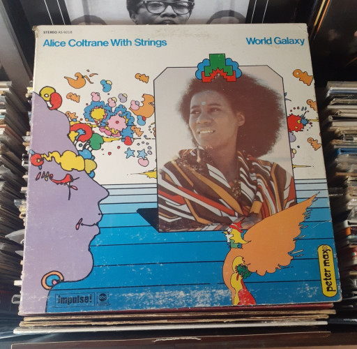 Colorful album cover features photo of Alice Coltrane and an abstract illustration by the artist Peter Max that has a vaguely "Yellow Submarine" vibe.