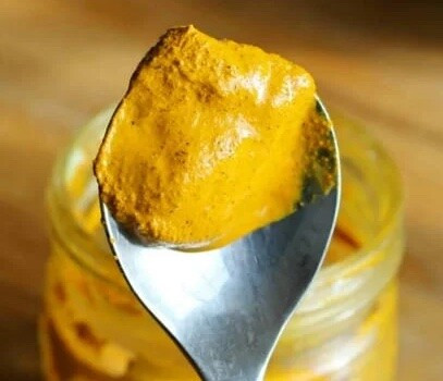 Close-up of a spoon holding a thick golden paste.