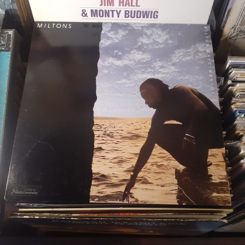 Album cover features a photo of MN  crouching at the edge of an ocean harbor, dipping his hand into the water.