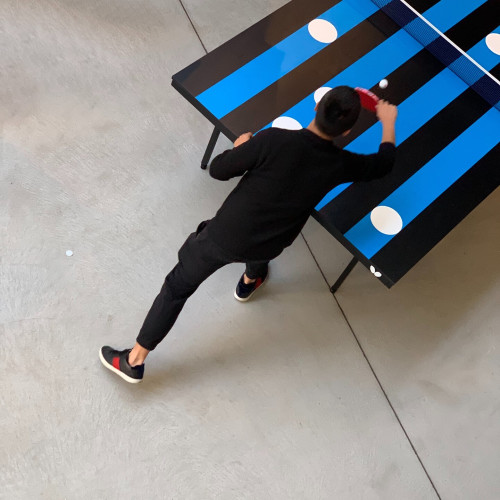 Photo prise de haut d’un joueur de ping-pong sur table lignée bleu et noir