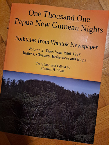 Large book with an orange cover and the photo of junge scenery. Title reads: One thousand and one Papua New Guinean nights, Folktales from Wantok Newspaper. Volume 2: tales from 1986-1997, Indices, glossary, references and maps. Translated and edited by Thomas H. Slone 