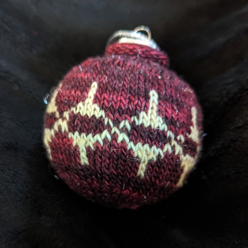 Day 3's bauble features colourwork in deep red and light butter yellow. There's a repeating motif that looks a bit like a child's spinning top or a fancy glass Christmas ball with elongated top and bottom. 