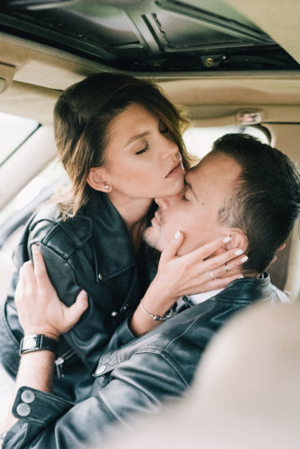 Attractive man and woman dressed in leather jackets embracing face-to-face inside a car. Source: Pexels
