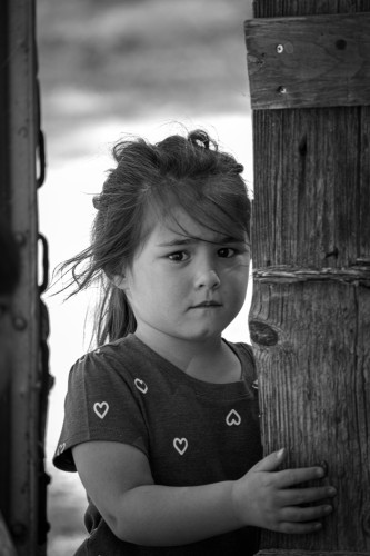 A young girl, with a worried expression, standing near a fence. Photo by Tony Mucci via UnSplash.