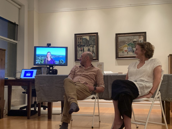 Rachel Cleves on a monitor via Zoom as Aram Sinnreich and Stephanie Grant, seated, listen