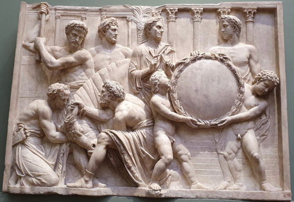 Relief in marble showing four men involved in a bull sacrifice. Two other men stand to the right; in front of them are two nude youths holding what appears to be a symbolic shield.