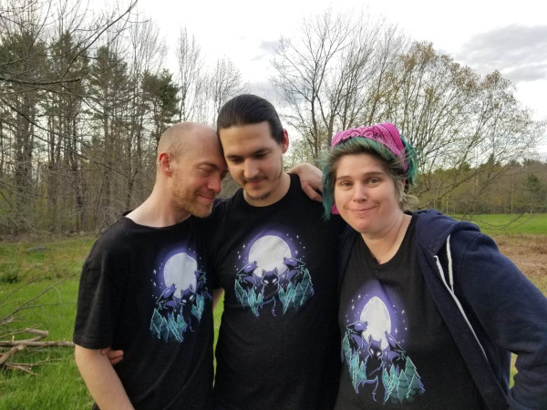 Three people, outside, mmf, all wearing the same tshirts with 3 wolves on them in the full moon.