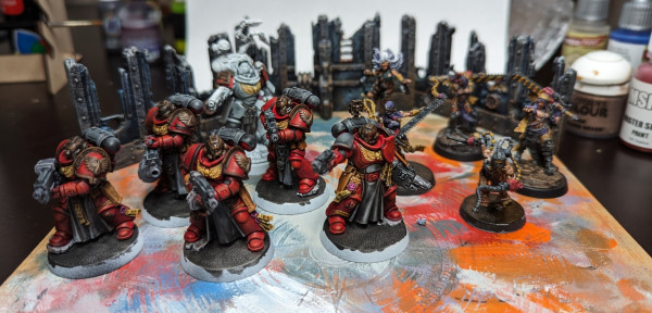 Warhammer 40k Space Marine Strenguard Veterans with some red paint, sisters of battle Repentia in purple with hazard stripe chainswords, a possessed breaking free of if her chains, and three ruined walls.