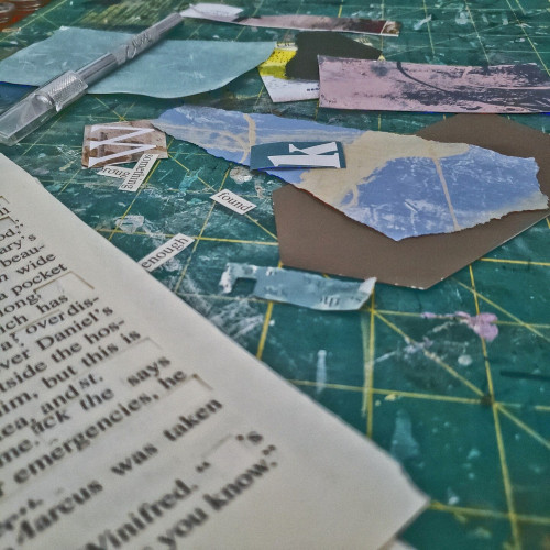 Various scraps of torn paper and book pages spread out across a green cutting mat.