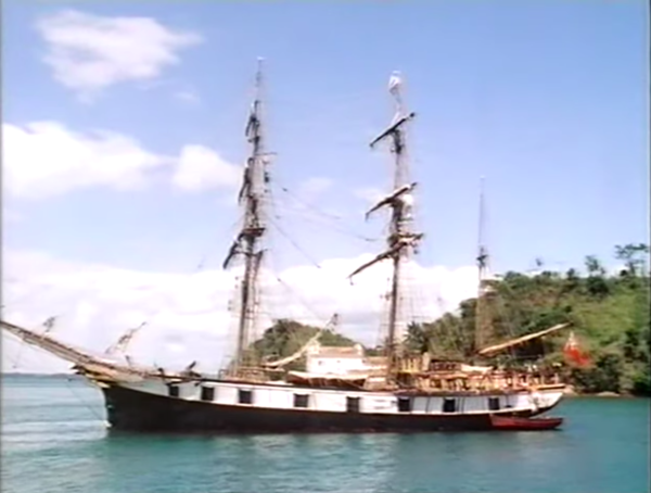 An 1800s ship pulled into a lovely blue bay