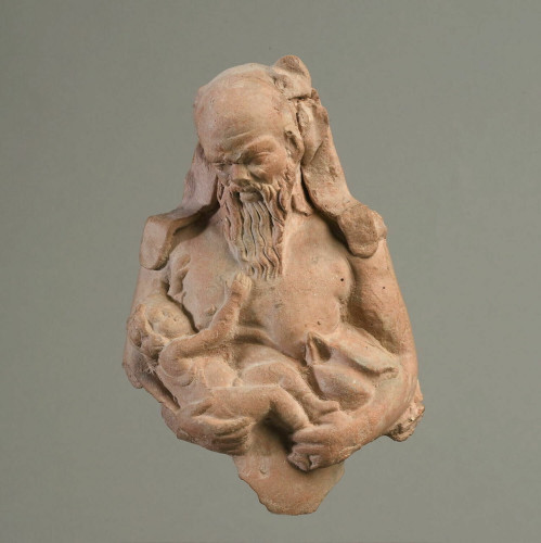 Figurine of Silenus, an old, bald, bearded satyr, holds the baby Dionysos in his arms. The lower part of the figure and several ivy leaves are missing.