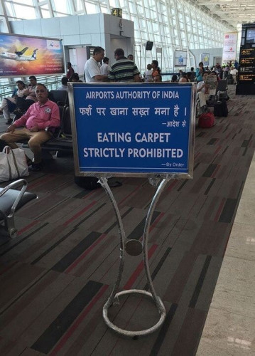 A sign at an airport in India on a section of carpet next to a tiled area: 

Eating Carpet Strictly Prohibited.