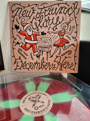 New Found Glory - December's Here album cover. A man in a Santa suit Dancing with a woman in a red Xmas dress with a NFG record playing between them.