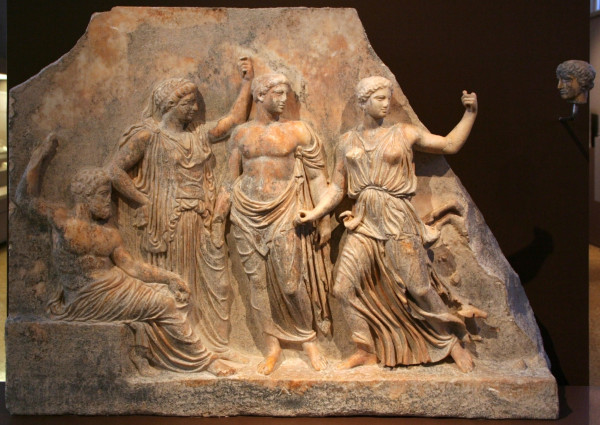 Marble relief of Zeus, seated, his arm raised over his head either holding his sceptre (now lost) or his thunderbolt. Leto stands beside him, her left arm raised, likely also originally holding a sceptre, now lost. Next to Leto stands Apollon and next to him Artemis. All of them are looking at something on the rightl