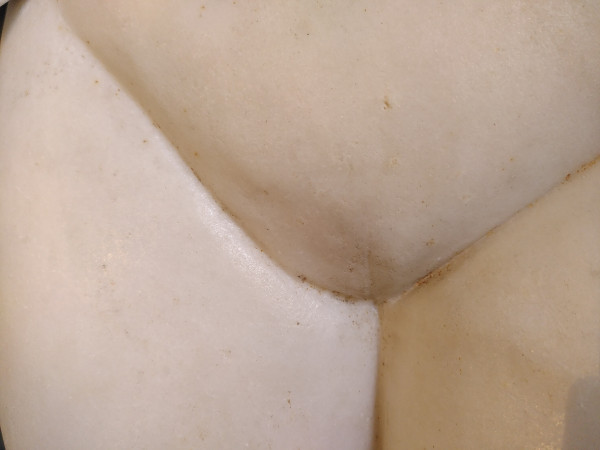 Close-up of the pubic triangle of a white marble Aphrodite sculpture. The slit is subtle but it is there.
