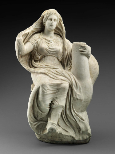 Aphrodite is seated on the back of the goose. She grasps the bird's neck with her left hand; her right hand is raised, holding out her mantle, and her feet are crossed. The goose was flying upward with wings spread. Its legs are hidden in the round plinth, once probably painted blue to represent the air. The goddess wears a short-sleeved chiton tied by a cord just below the breast and held up under the arms by another cord passing over her shoulders and crossed at the back. The voluminous himation covers her legs and her left arm and is drawn up over her head. Her hair is arranged in wavy locks rising vertically above the forehead.