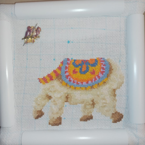 A half-finished cross stitch of an alpaca.