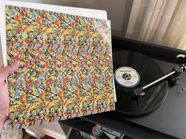 The inner sleeve of Tapers Choice Vol 1, featuring a magic eye. In the background is a turntable playing the record.