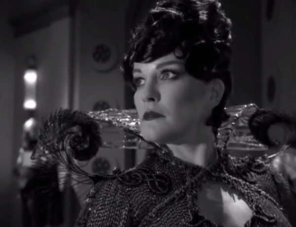 Janeway cosplaying as the Spider Queen in an elaborate outfit with black wig. All in black and white