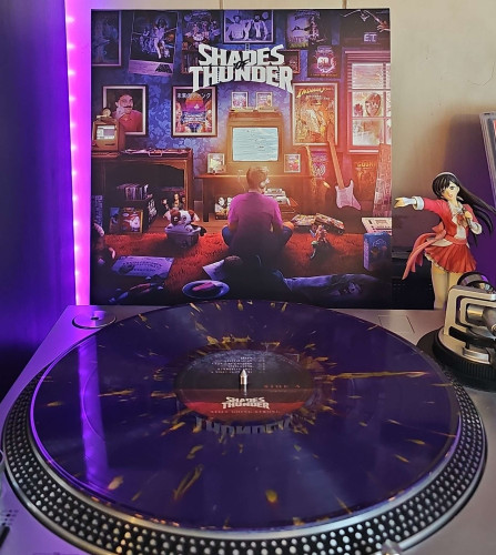 A purple with yellow splatter vinyl record sits on a turntable. Behind the turntable, a vinyl album outer sleeve is displayed. The front cover shows a man sitting on the floor in  a room filled with 80s vintage items and posters. 

To the right of the album cover is an anime figure of Yuki Morikawa singing in to a microphone and holding her arm out. 