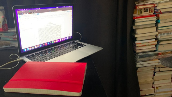 A mysterious writer's desk, with a pile of books behind a curtain in the background.