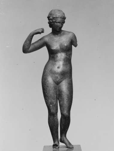 Nude bronze statuette of the Aphrodite Anadyomene type. By referencing other copies of this type, one can conclude that the figure's left forearm was raised in a manner similar to the right one. She is probably shown in the act of arranging her hair and may even be grasping the ends of the fillet wound about her hair to tie it off. However, since the attribute she held in her hands is missing, various reconstructions are possible. It has also been suggested that the goddess is represented as adorning herself with jewelry. The variant exemplified here was clearly popular in this size and medium, since several examples are known.