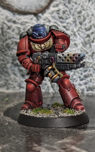 A Warhammer 40k Space Marine miniature painted as a Blood Angels color scheme with red armor and black accents. The flamers were fun to paint, lots of practice with the heat damage.