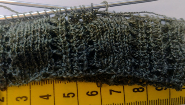 Beginning of a knitting project with a tape measure for scale.

It's very fine, green yarn with small needles, about 2 cm high at this point.