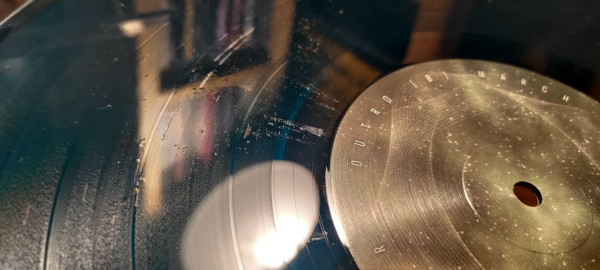 A vinyl record with severe quality issues: no-fills, and foreign objects (sand?) pressed into the vinyl.