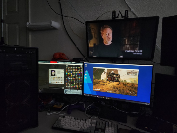 Three monitors on a desk. The leftmost is playing minecraft, the bottom-right is playing Satisfactory over a VirtualBox VM, the top right is showing a YouTube video, and there are two powered off monitors visible on the edge of the image