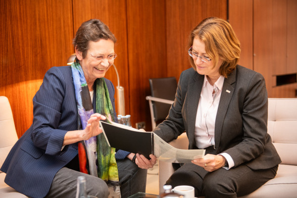 Bettina Sokol und Antje Grotheer sitzen nebeneinander in der Sitzgruppe im Präsidentenbüro. Sie gucken gemeinsam in den aufgeschlagenen Sonderbericht.
