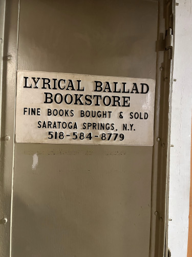 A white metal sign on a grey steel door that reads

Lyrical Ballad Bookstore
Fine Books Bought & Sold
Saratoga Springs, N.Y.
518-584-8779

