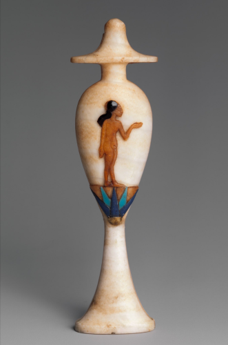 This perfume bottle, with a depiction of an Amarna princess standing upon a blue lotus blossom, is in the shape of a hes-vase (used for libations in temples). It is made from Egyptian alabaster, with an inlay of coloured glass, carnelian, obsidian and gold. The princess is naked and brown-skinned, and her head mostly shaved, save a long side-lock of black hair. Her left hand is raised, palm up, in a gesture of greeting or worship. She stands on the flat top of a giant blue lotus blossom, newly opened with the morning sun. For an Egyptian, the child and the flower would have been a powerful image of rebirth and rejuvenation.

The hes vase is named after the 'hes' hieroglyphic, which means to favor or praise someone.

Met Museum (40.2.4)