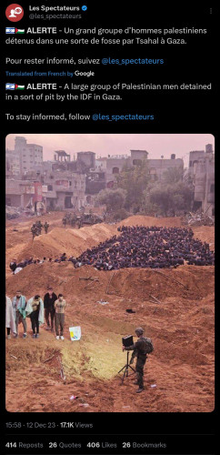A large group of Palestinian men detained in a pit by soldiers, surrounded by rubble and damaged buildings.