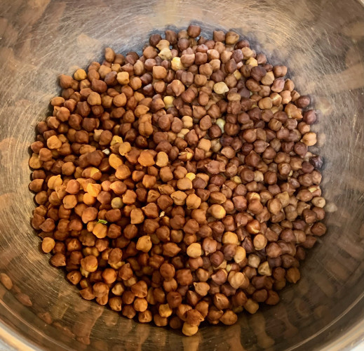 A bowl of dark brown smallish chickpeas: the cooked desi chickpeas, seed coat still on.
