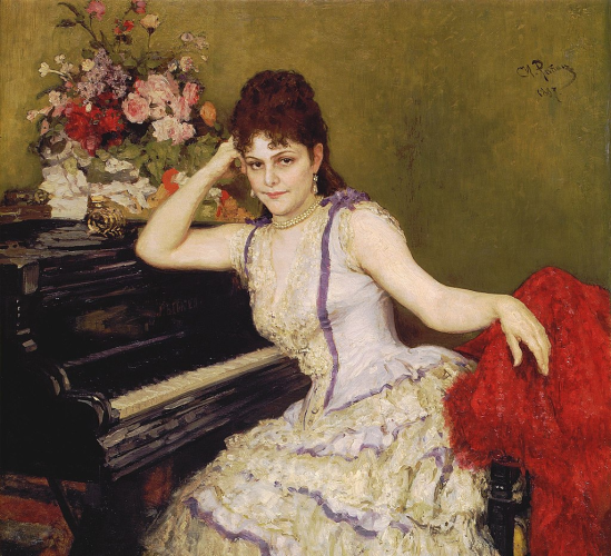 A painted portrait of Sophie Menter by Ilya Repin. Sophie has her brown hair curled, and it is pulled up and back away from her face. She wears a lacy gown and pearls, sitting at a piano, where she looks straight out at the viewer.
