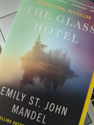 Picture of the cover of a paperback copy of "The Glass Hotel" by Emily St. John Mandel. The cover shows a small wooded island in what seems to be early morning light and mist.