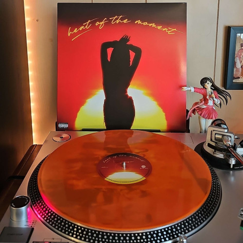 A Sunburst vinyl record sits on a turntable. Behind the turntable, a vinyl album outer sleeve is displayed. The front cover shows Tink's silhouette in front of the sun. 