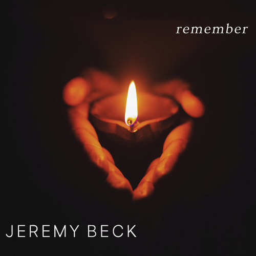 Cover of Jeremy Beck’s Neuma Records album “remember”, featuring a photo of a pair of hands cupping a lighted candle, on a black background, with only the hands/candle lit up.