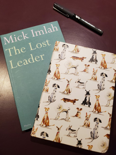 The poetry collection The Lost Leader by Mick Imlah (Faber and Faber) sits on a purple desktop with a notebook with a cover of cartoon dogs